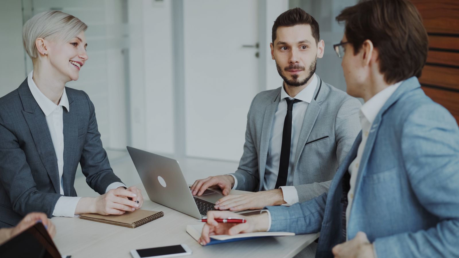 Equipo directivo en una reunión de trabajo alrededor de un portátil