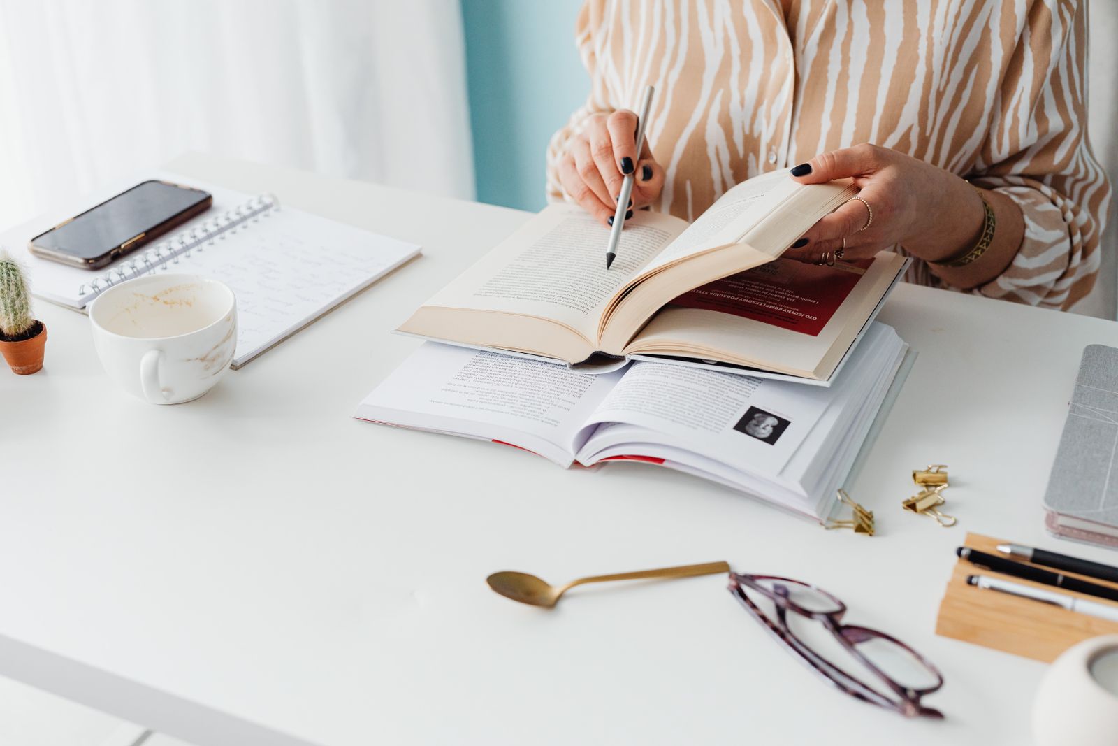 Investigadora tomando notas entre libros y apuntes en su escritorio