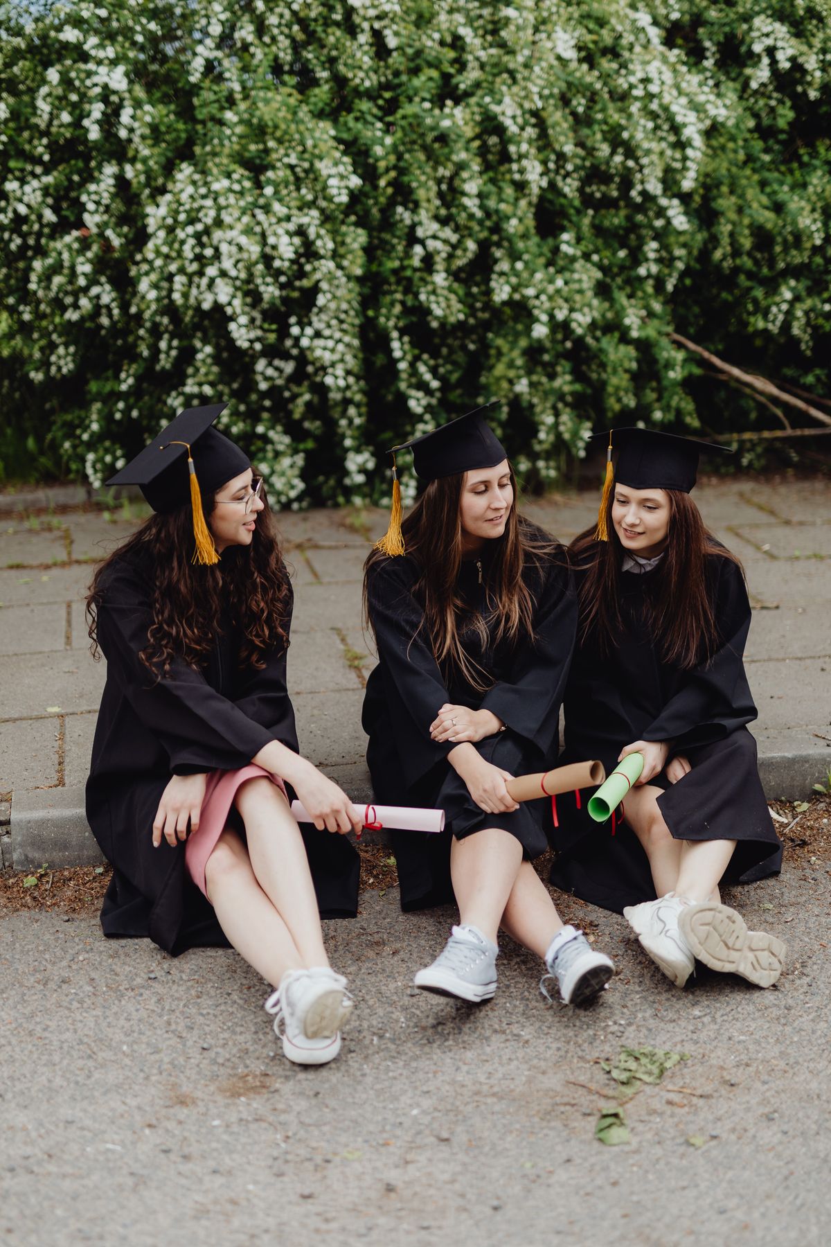 Tres graduadas conversando con sus diplomas al aire libre